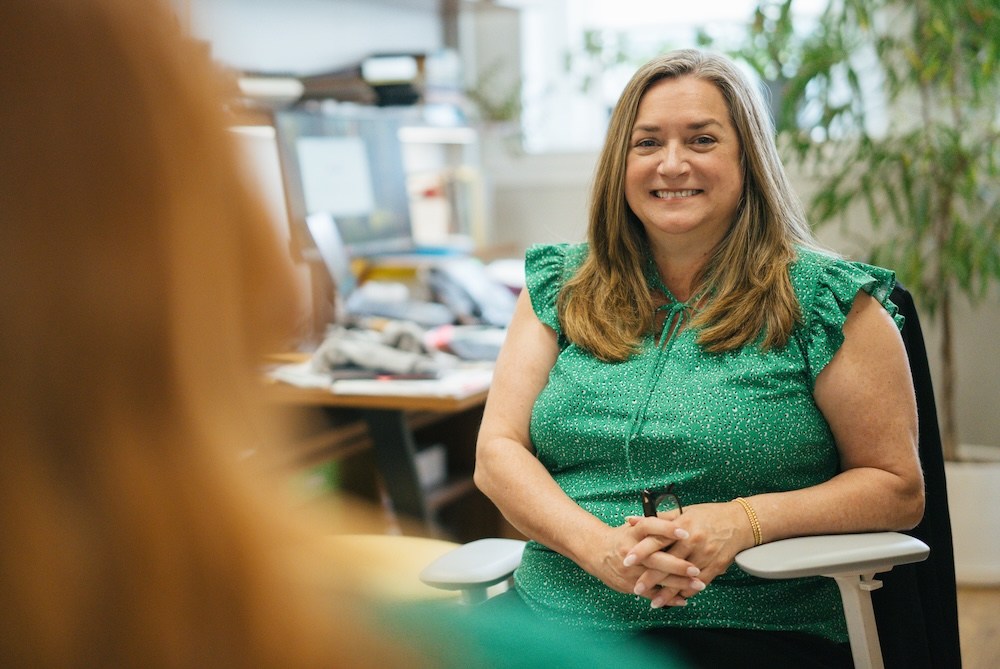 Leah Tolliver, assistant dean of wellness in Marshall University's Division of Student Affairs, smiles while meeting with a student in her office.